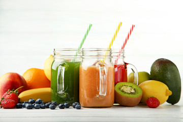 Sweet smoothie in glass jars with fruits on white wooden table