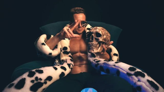 Sexy man with a skull sits in a chair