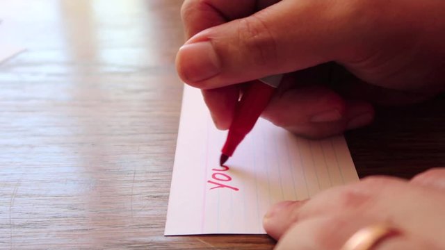 close up footage as male hands write a note using permanent marker pen on a small card of paper