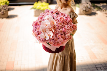 Young girl holding in her hands a huge box of peony roses