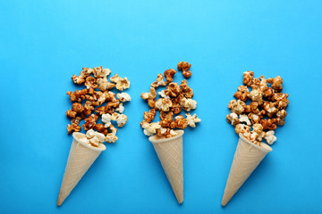 Caramel popcorn in waffle cones on blue background