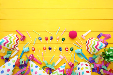 Birthday paper caps with candles and blowers on yellow wooden table