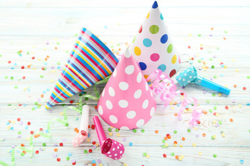 Birthday paper caps with blowers and confetti on wooden table