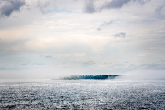 Beautiful nordic archipelago summer view  of a island surrounded by thick haze and fog at the horizon.