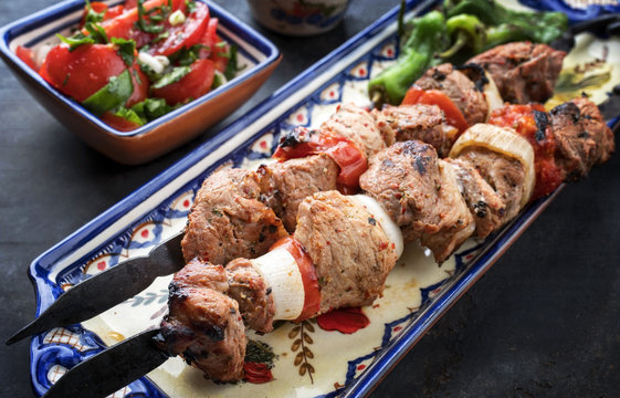 Traditional Greek souvlaki barbecue skewer  tomato onion salad and paprika as closeup on a plate
