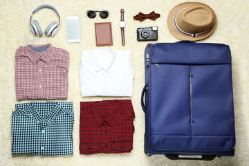 Blue suitcase with clothes, headphones, smartphone and passport
