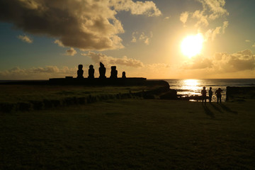 People watching beautiful sunset over the Pacific ocean at Ahu Tahai with Moai statues, Easter Island of Chile 