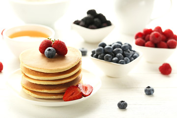 Tasty pancakes with berries on white wooden table