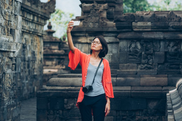 Asian female solo travelers use smartphone selfie herself with ancient buildings- Borobudur temple- Java -Indonesia- Asia.