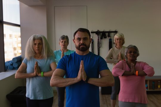 Trainer And Group Of Senior Women Performing Yoga