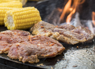Grillparty BBQ mit Lachs Fleisch und Mais auf dem offenen Grill mit Flamme