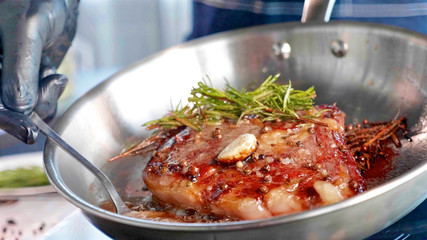 Meat steak with seasonings and herbs hissing on frying pan, close-up