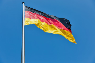German flag on the flagstaff waving against clear blue sky