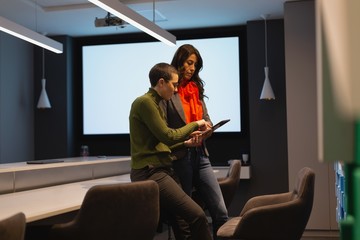 Business colleagues talking over digital tablet in office