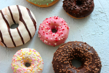 Photos of different donuts. Assorted colorful donuts in pink, green, chocolate icing close-up, sweet dessert.