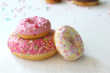 Photos of different donuts. Assorted colorful donuts in pink, green, chocolate icing close-up, sweet dessert.