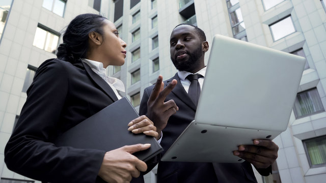 Afro-American businessman giving instructions to assistant, working on project