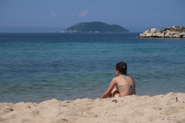 Fototapeta na wymiar A girl on the beach looking at the sea