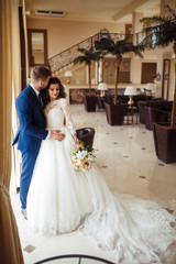 Naklejka premium Beautiful Bride and Groom enjoy each other in the nice hall of the hotel. happy romantic young couple celebrating their marriage.Sexy kissing stylish couple of lovers close up portrait. wedding