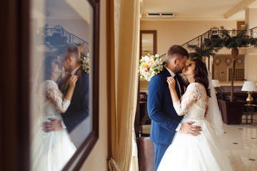 Fototapeta premium Beautiful Bride and Groom enjoy each other in the nice hall of the hotel. happy romantic young couple celebrating their marriage.Sexy kissing stylish couple of lovers close up portrait. wedding