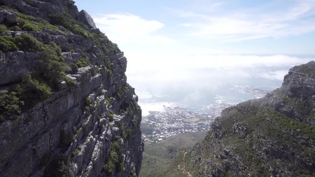 Close up view of a Table Mountain cliff to the Atlantic Ocean and Cape Town above a mans feet on the edge