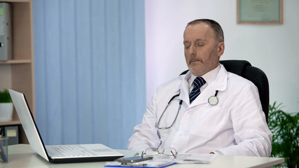 Fototapeta premium Tired chief physician relaxing after exhausting working day, stressful job