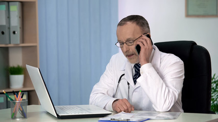Obraz premium Experienced physician talking on phone, consulting patient about treatment