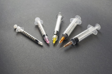 Syringes with different needles on a dark background