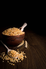 Сhopped peas in a wooden bowl on a wooden background near the ears of wheat. wooden spoon with chopped peas