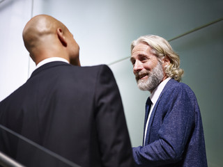 two corporate executives talking while ascending stairs