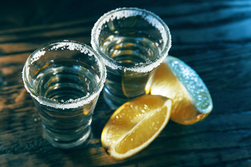 Two tequila and lime slices on a wooden background in the bar