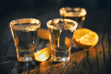 Three glasses of alcohol and lime on a dark background in the bar