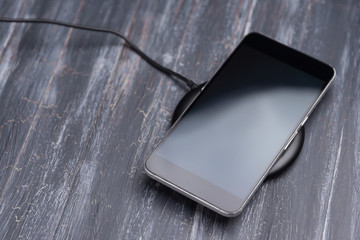 Mobile phone on wireless charging on a gray background © jalisko
