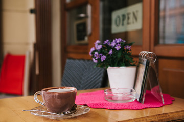 A cup of hot chocolate or coffee on the table in a cozy outdoor cafe.