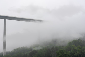 High modern bridge vanishing into mist and clouds