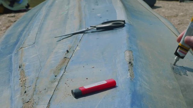 Process of reparing canoe. Man tapes hole on bottom of canoe