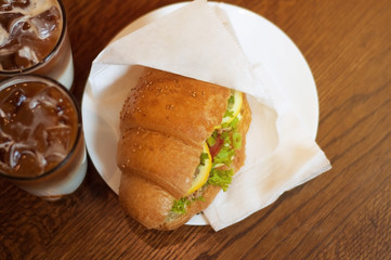 croissant sandwiches and ice coffee cups on wooden table. Top view