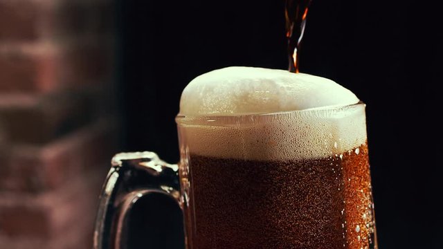 Amber beer poured into mug ib slow motion