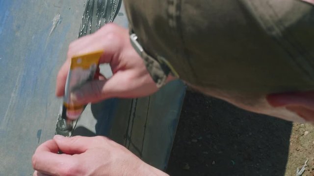 Process of reparing canoe. Man tapes hole on bottom of canoe