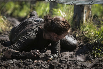 Muddy obstacle race runner in action. Mud run.