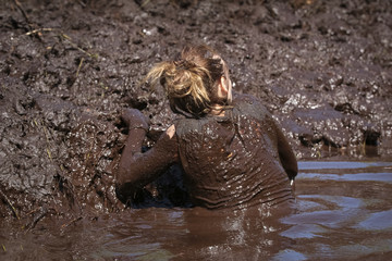 Muddy obstacle race runner in action. Mud run.
