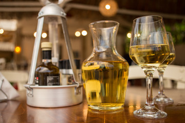 Pouring white wine into the glass against wooden table. Romantic dinner.