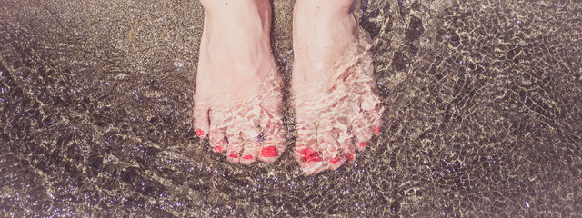 feet in water, female feet in the sand sea.