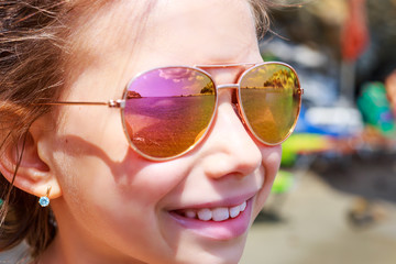 Beautiful young girl in sunglasses with sea rerlection. rerlection Holidays, travel, vacation and happiness concept.
