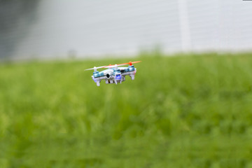 small drone with a camera flying over the grass