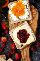 Toast bread with homemade strawberry jam and apricot marmalade on rustic table served with butter for breakfast or brunch
