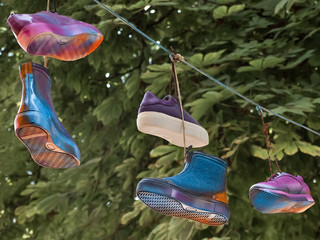 Different shoes hanging on a cord laced with the laces. Cultural diversity symbolically shown. For...