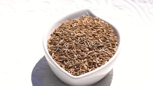 Dry spices cumin seeds on a rotary table. 4K. Macroshooting.
