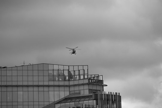 Helicopter lands on the roof of a glass skyscraper in cloudy weather
