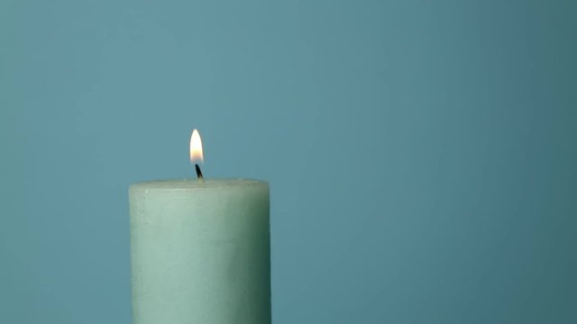 Close up light blue candle trembling flame